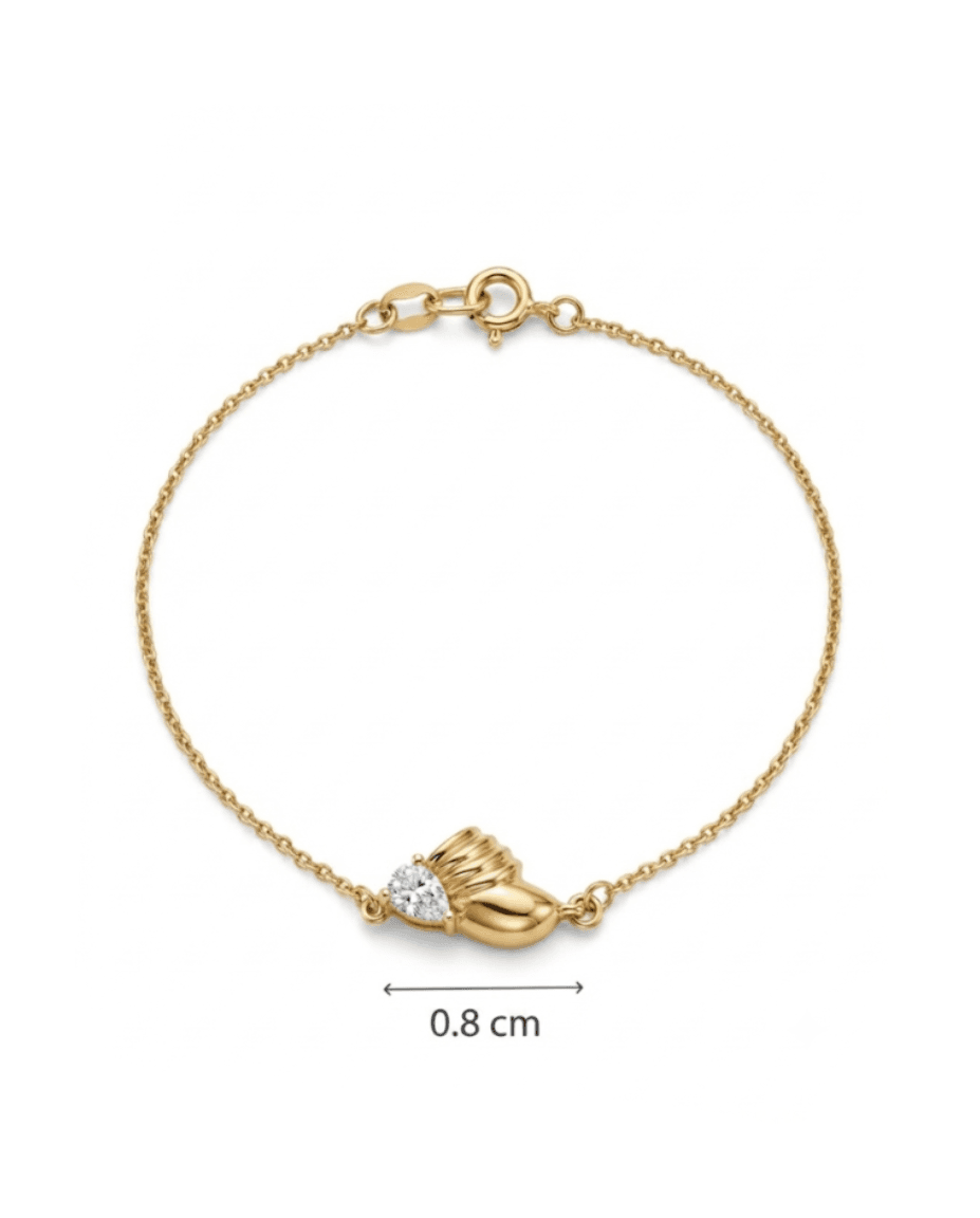 A delicate gold chain bracelet with a small gold baby boot charm holding a heart-shaped clear gemstone, shown on a white background with a 0.8 cm size indicator below.