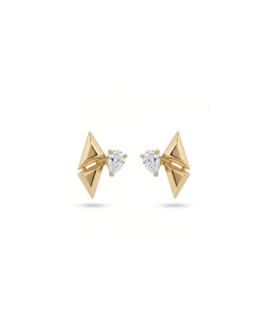 A pair of gold geometric stud earrings with triangular pyramid shapes and a small pear-cut clear gemstone in the center, set against a plain white background.