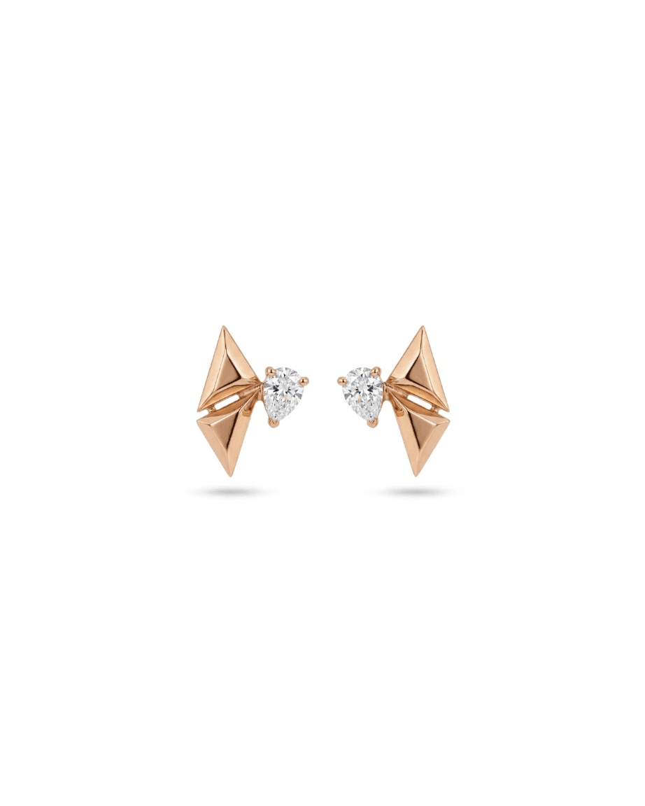A pair of rose gold geometric stud earrings with triangular facets and a small pear-cut clear gemstone in the center, shown on a white background.